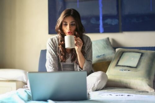 What is Keto coffee, a woman holding a coffee mug while sitting on her bed with a latptop